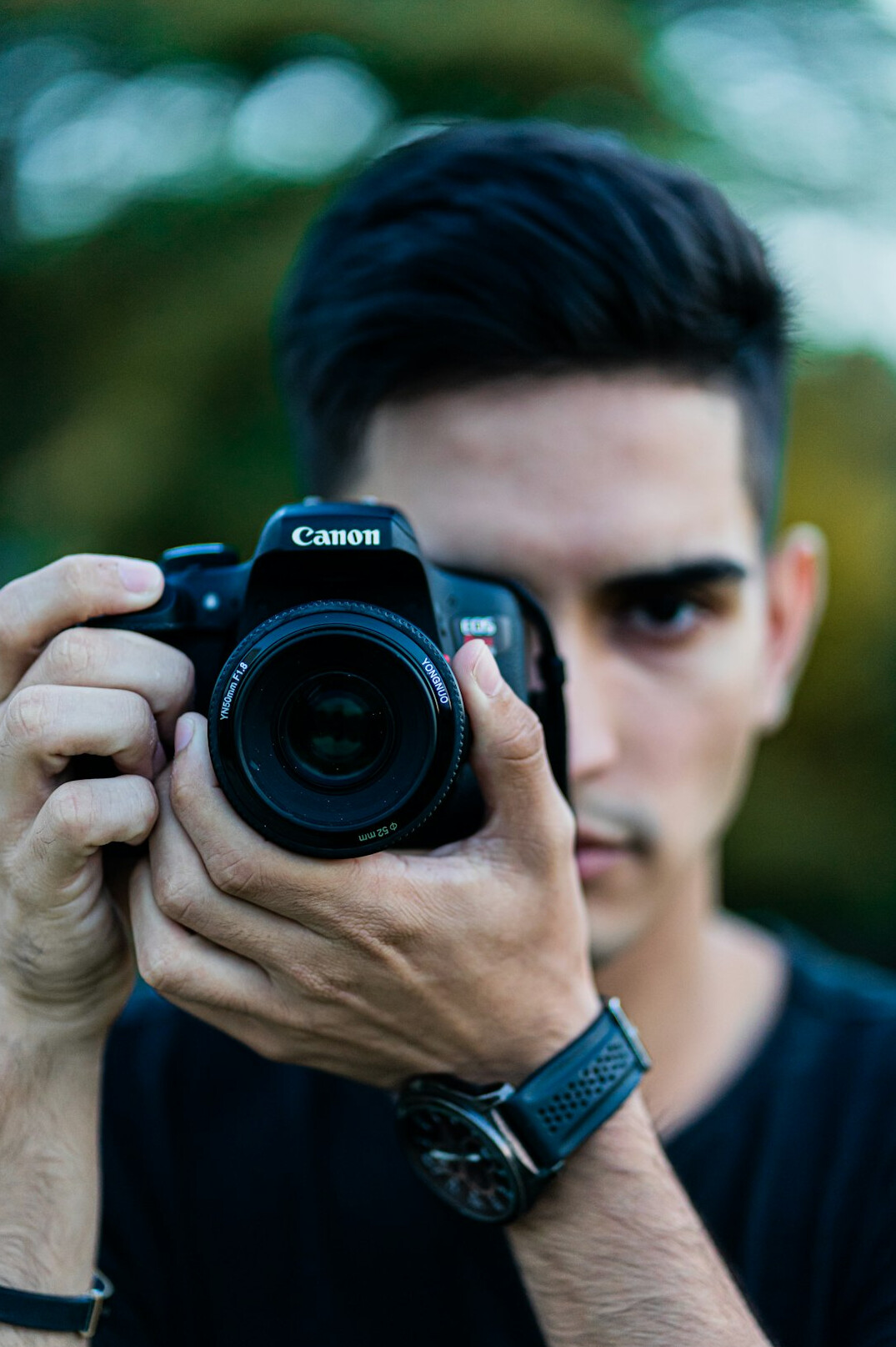Man holding a camera looking at the viewer