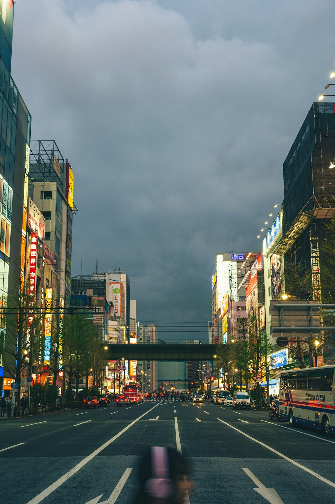 Busy city street with pedestrians crossing at dusk